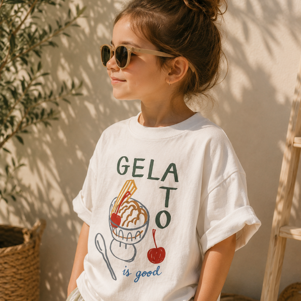 Person wearing a white t-shirt with 'GELATO is good' text and graphics, standing outdoors.